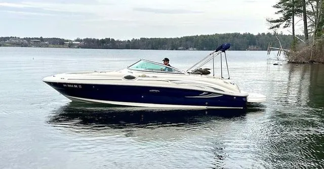 Slide: The Image of 2005 Sea Ray 240 Sundeck boat on a calm lake with trees in the background. - 4