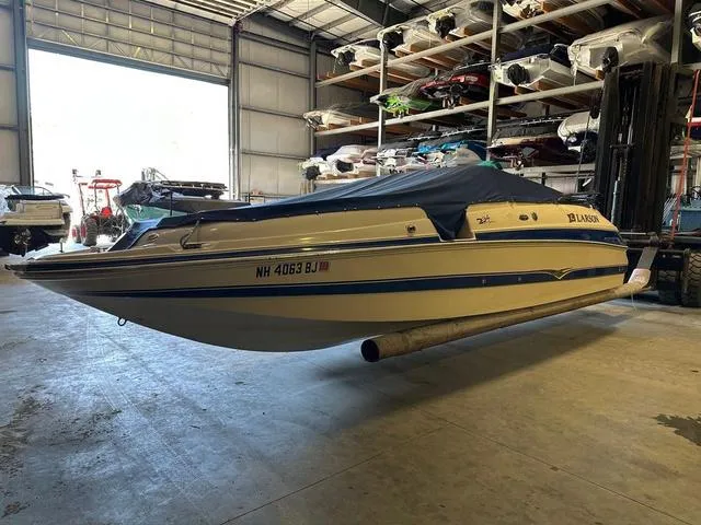 Slide: The Image of 2003 Larson 234 ESCAPE boat in storage, covered, with visible registration number. - 3