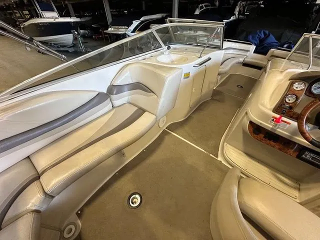 Slide: The Image of 2003 Larson 234 ESCAPE boat interior with beige seating and dashboard, in a showroom. - 8