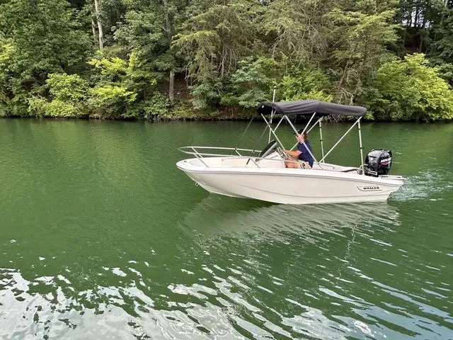 Slide: The Image of 2024 Boston Whaler 130 Super Sport cruising on a serene, green river. - 1