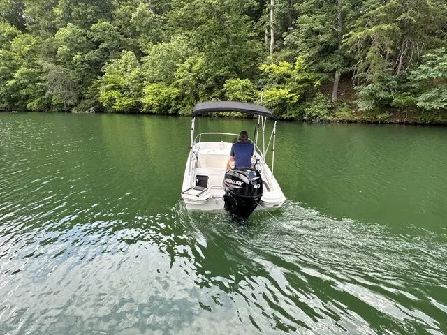 Slide: The Image of 2024 Boston Whaler 130 Super Sport on a serene lake, surrounded by lush greenery. - 2