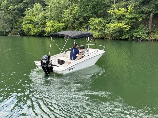 Slide: The Image of 2024 Boston Whaler 130 Super Sport boat cruising on a serene, green lake. - 3