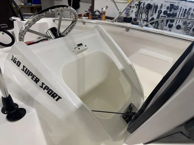 Slide: The Image of 2025 Boston Whaler 160 Super Sport boat console with steering wheel and storage compartment. - 11