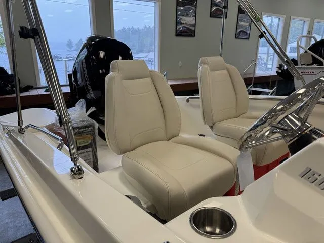 Slide: The Image of 2025 Boston Whaler 160 Super Sport interior with white leather seats and modern steering console. - 13