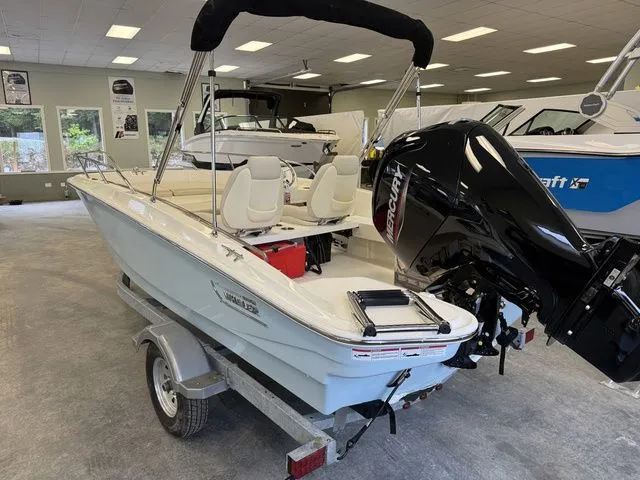 Slide: The Image of 2025 Boston Whaler 160 Super Sport boat on trailer in showroom, featuring Mercury outboard engine. - 3