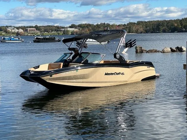 Slide: The Image of 2023 MasterCraft NXT22 boat on a calm lake with scenic background. - 1