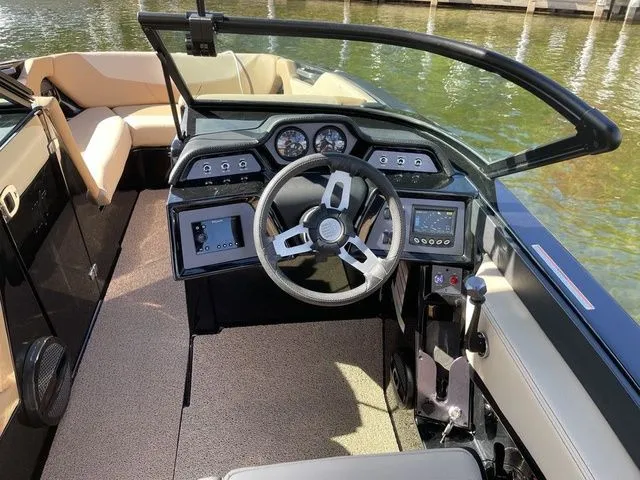 Slide: The Image of 2023 MasterCraft NXT22 boat interior with modern dashboard and steering wheel on a sunny day. - 11