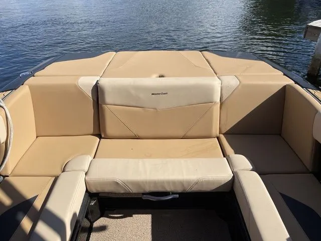 Slide: The Image of 2023 MasterCraft NXT22 boat interior with beige seating, on a calm lake. - 13