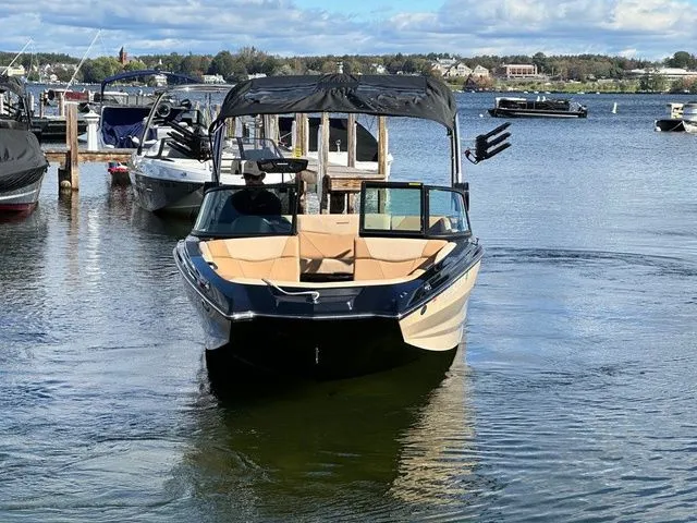 Slide: The Image of 2023 MasterCraft NXT22 boat docked on a calm lake under a partly cloudy sky. - 3