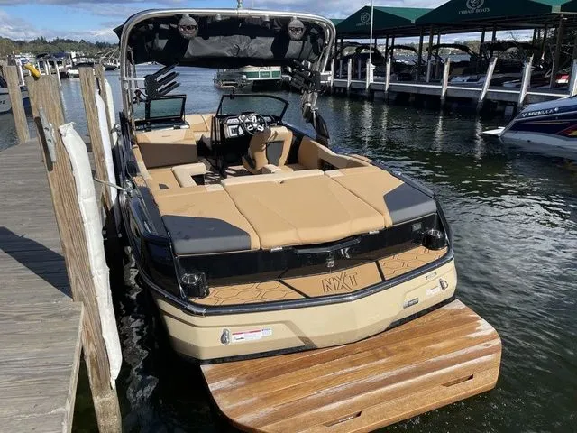 Slide: The Image of 2023 MasterCraft NXT22 boat docked at a marina, featuring tan upholstery and sleek design. - 4
