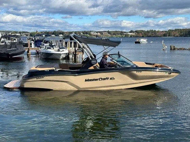 Slide: The Image of 2023 MasterCraft NXT22 boat on a lake, with a person at the helm, under a cloudy sky. - 5