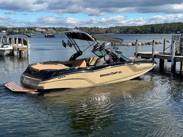Slide: The Image of 2023 MasterCraft NXT22 boat docked on a scenic lake under a cloudy sky. - 6