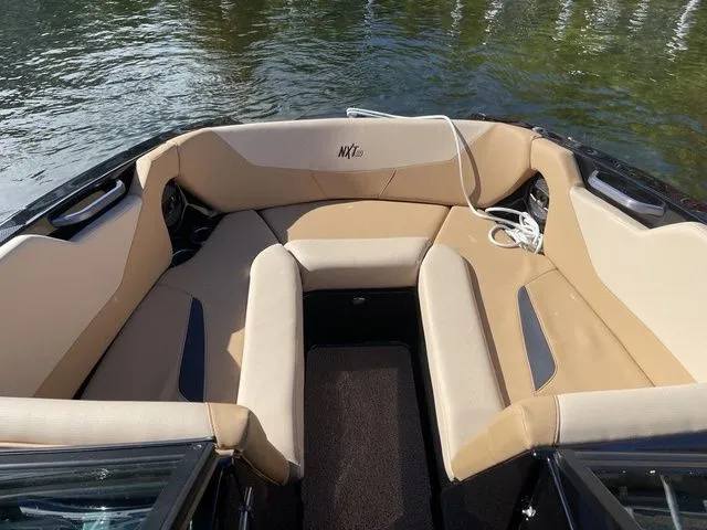 Slide: The Image of 2023 MasterCraft NXT22 boat interior with tan seating, on calm water. - 8