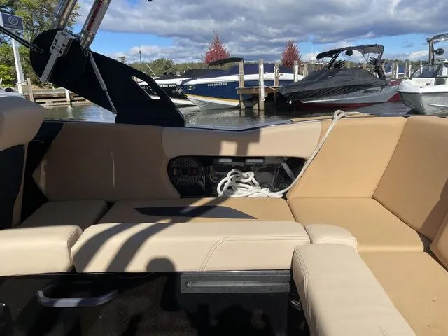 Slide: The Image of 2023 MasterCraft NXT22 boat interior with beige seating, docked near other boats. - 9