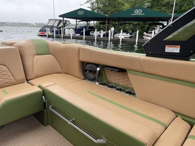 Slide: The Image of 2023 MasterCraft X24 boat interior with tan and green seating, docked near water. - 12