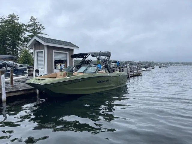 Slide: The Image of 2023 MasterCraft X24 boat docked on a cloudy day at a lakeside marina. - 2