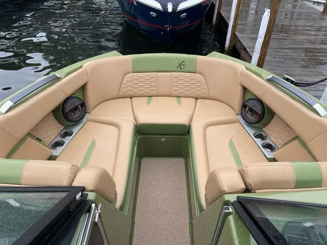 Slide: The Image of 2023 MasterCraft X24 boat interior with tan and green seating, cup holders, and speakers. - 4
