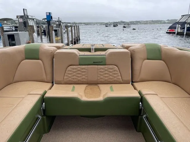 Slide: The Image of 2023 MasterCraft X24 boat interior with tan and green seating at a dock. - 5
