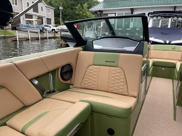 Slide: The Image of 2023 MasterCraft X24 boat with tan and green interior, docked near waterfront homes. - 9
