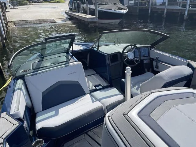 Slide: The Image of 2024 MasterCraft ProStar boat interior with sleek seating and modern dashboard, docked by the water. - 7