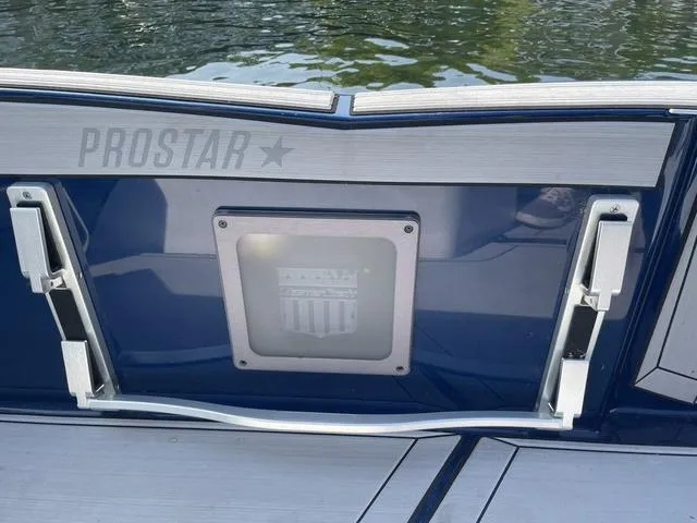 Slide: The Image of 2024 MasterCraft ProStar boat stern detail with logo, on calm water. - 8