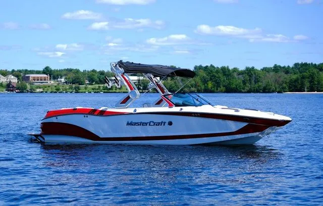 Slide: The Image of 2023 MasterCraft X24 boat on a lake with a scenic forest backdrop. - 3