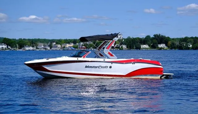 Slide: The Image of 2023 MasterCraft X24 boat on a lake with a scenic background. - 6