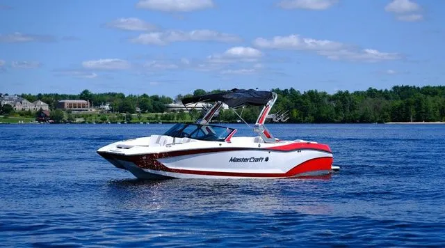 Slide: The Image of 2023 MasterCraft X24 boat on a lake with a scenic background. - 7
