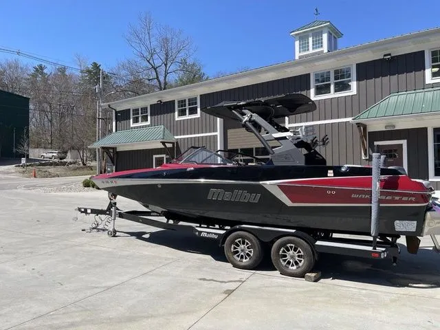 Slide: The Image of 2017 Malibu 22 MXZ boat on trailer, new engine and transmission, parked outside a building. - 2