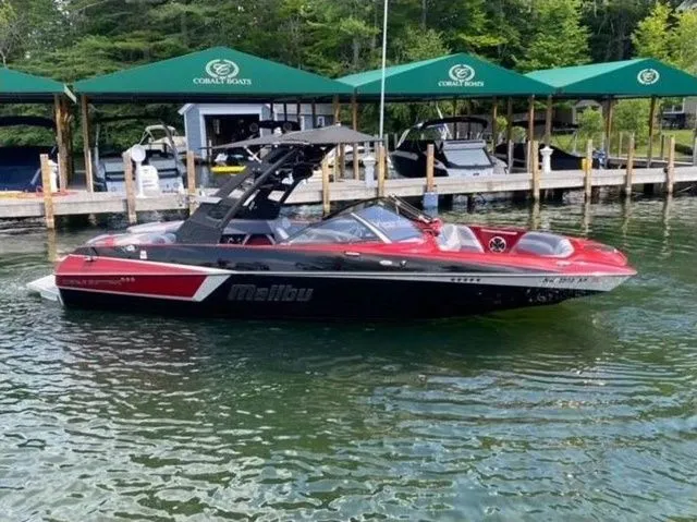 Slide: The Image of 2017 Malibu 22 MXZ boat with new engine and transmission, docked on a serene lake. - 5