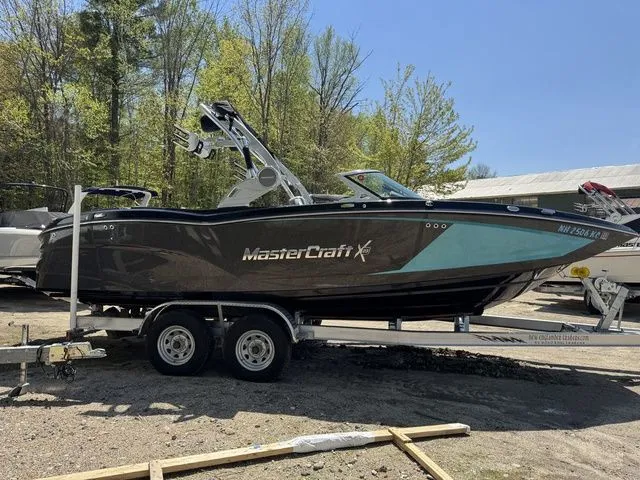 Slide: The Image of 2018 MasterCraft X23 boat on trailer, parked outdoors with trees in background. - 4