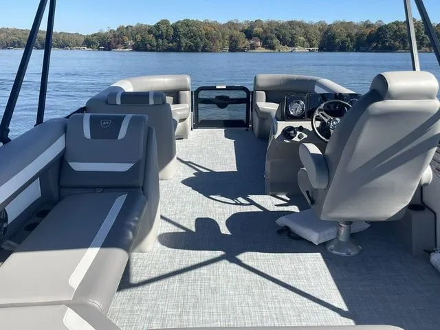 Slide: The Image of 2025 Premier 220 Sunscape RF pontoon boat interior with gray seating on a sunny lake. - 5