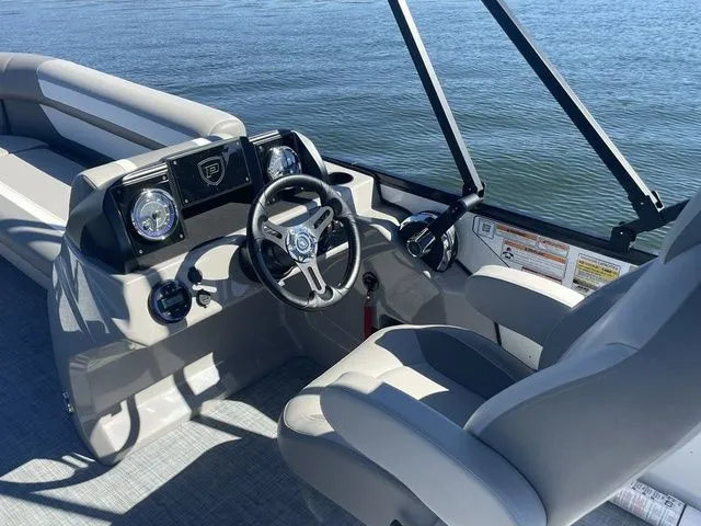 Slide: The Image of 2025 Premier 220 Sunscape RF boat interior with steering wheel and dashboard, on calm water. - 6