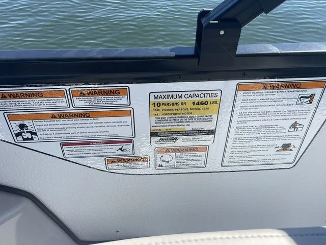 Slide: The Image of 2025 Premier 220 Sunscape RF boat capacity and safety warning labels by the water. - 9