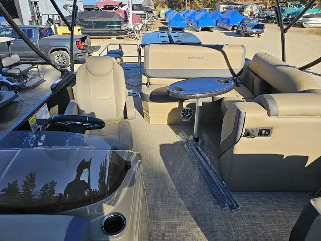 Slide: The Image of 2025 Sylvan MIRAGE X3 DLZ BAR interior with beige seating and round table. - 8