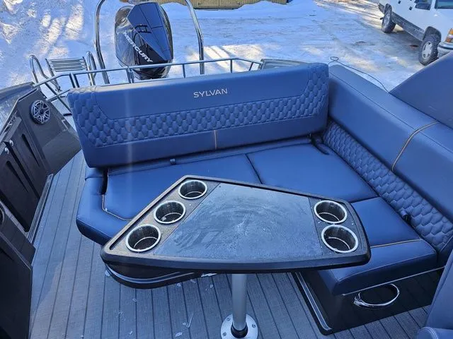 Slide: The Image of 2025 Sylvan M3 CLZ DC boat interior with blue seating and cupholder table. - 19