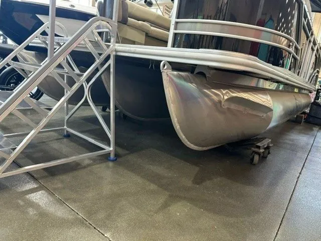 Slide: The Image of 2023 Sylvan 8524 CLZ pontoon boat with metal stairs, displayed indoors. - 2