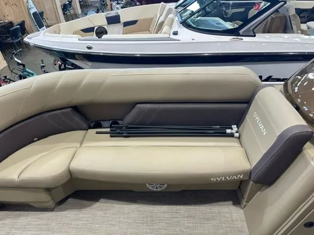 Slide: The Image of 2023 Sylvan 8524 CLZ boat interior with beige seating and folded canopy poles. - 7