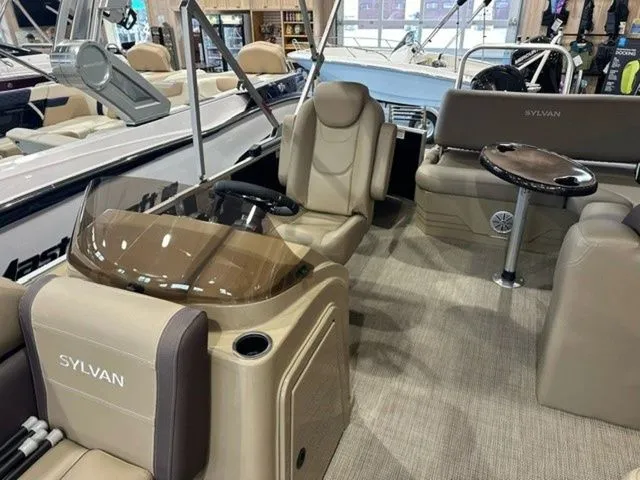 Slide: The Image of 2023 Sylvan 8524 CLZ boat interior with beige seating and modern dashboard. - 8