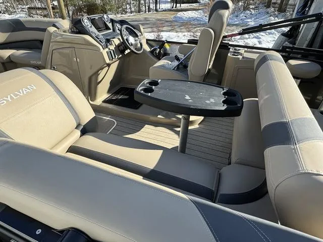 Slide: The Image of 2023 Sylvan L-3 DLZ BAR boat interior with beige seating and a central table. - 9