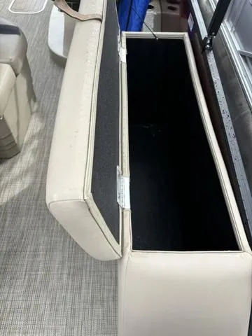 Slide: The Image of Open storage compartment in 2023 Sylvan L-3 DLZ boat, featuring beige seating and carpeted interior. - 7
