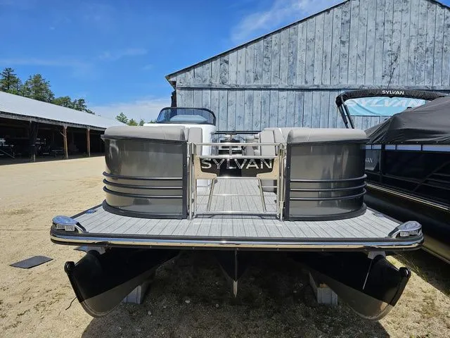 Slide: The Image of 2023 Sylvan S3 LZ pontoon boat displayed outdoors near a rustic building. - 3
