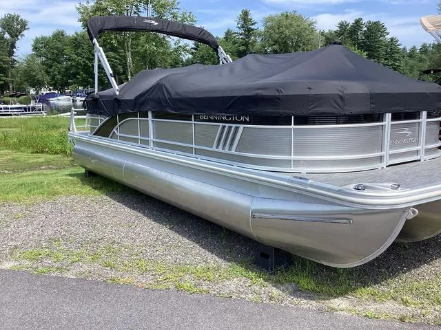 Slide: The Image of 2022 Bennington 24 LSRC pontoon boat with cover, parked on grass. - 1