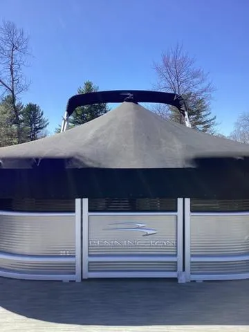 Slide: The Image of 2022 Bennington 24 LSRC pontoon boat with cover, set against a clear blue sky. - 18