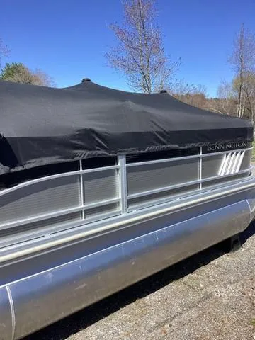 Slide: The Image of 2022 Bennington 24 LSRC pontoon boat with cover, parked outdoors. - 21