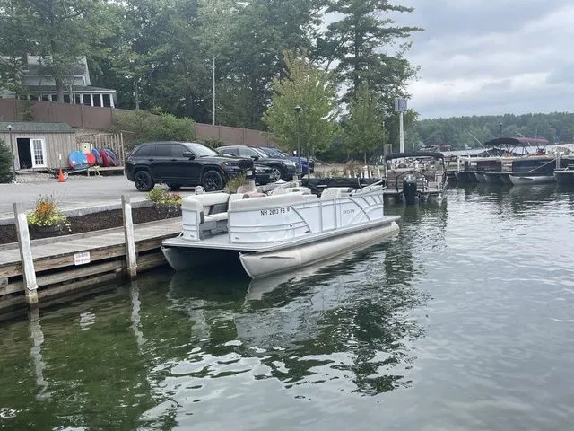 Slide: The Image of 2022 Sylvan 8522 LZ pontoon boat docked at a lakeside marina. - 2