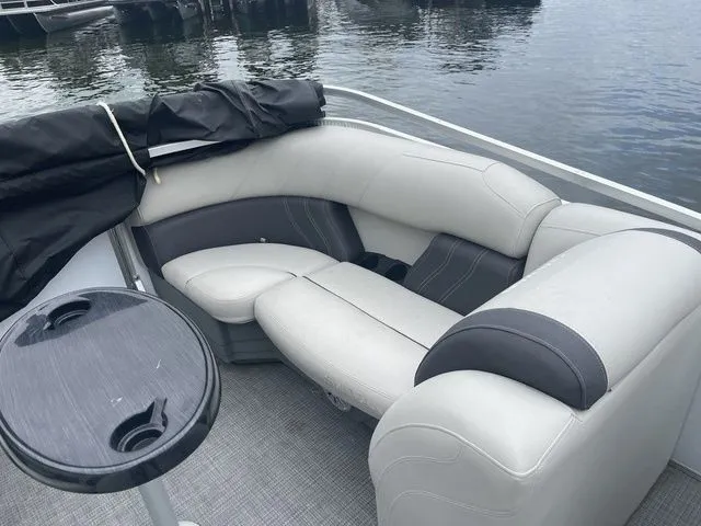 Slide: The Image of 2022 Sylvan 8522 LZ pontoon boat with plush seating and table on calm water. - 6