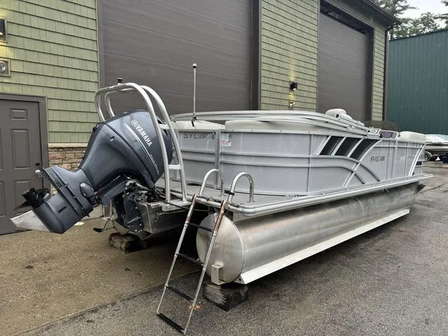 Slide: The Image of 2022 Sylvan 8522 LZ pontoon boat with Yamaha motor, parked outside a garage. - 5