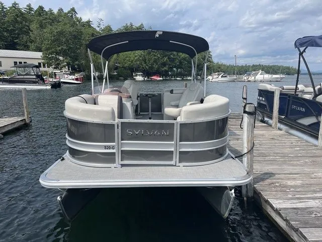 Slide: The Image of 2022 Sylvan 8520 LZ pontoon boat docked on a scenic lake. - 2