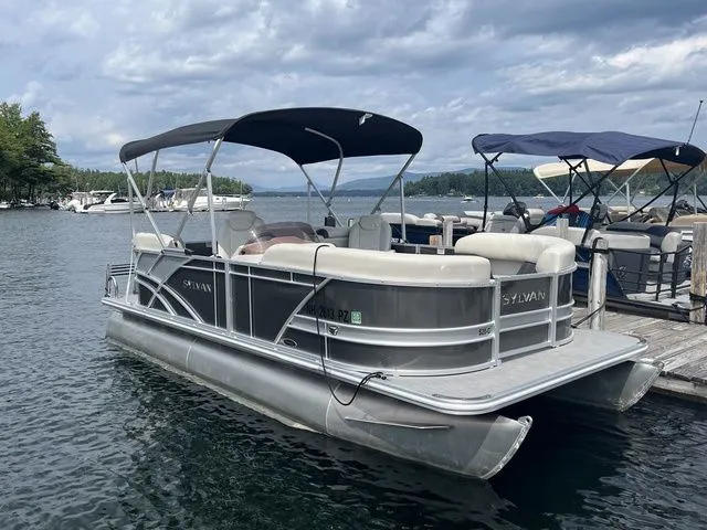Slide: The Image of 2022 Sylvan 8520 LZ pontoon boat docked on a lake under cloudy skies. - 3